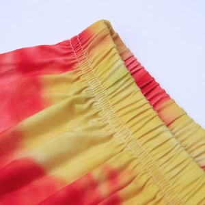 Detail of elastic waistband on tie-dye beach shorts with red and orange gradient patterns