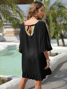 Détail d'une robe de plage avec pompons colorés et dos nu avec des liens à nouer