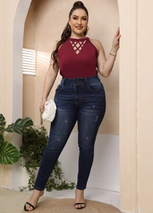 Detail of burgundy halter top with geometric cut-out neckline and high-waisted jeans