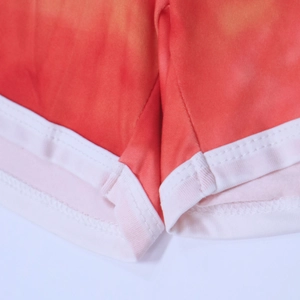 Detailed close-up of white ribbed edge and double stitching on tie-dye beach shorts