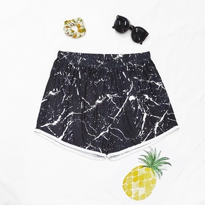 Detailed view of women's black marble print beach shorts with white contrast piping