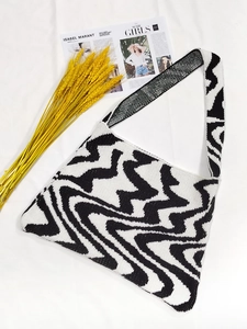 Knitted shoulder bag with black and white wavy geometric patterns on white background