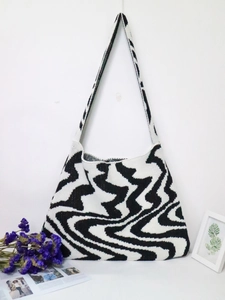 Close-up of black and white wave pattern knitted shoulder bag on white background