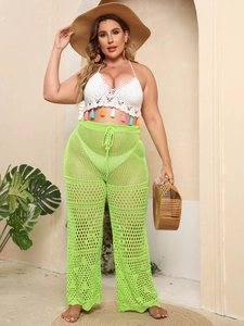 Detail of handmade crochet halter top with colorful tassels and green mesh pants