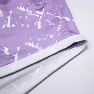 Detailed macro view of purple tie-dye fabric with white ribbed elastic hem and fine stitching