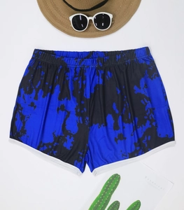 Detail view of summer beach shorts featuring blue tie-dye pattern and white piping trim