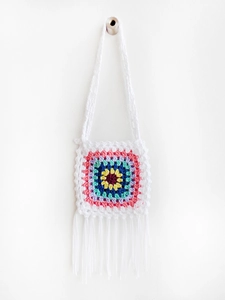 Close-up of handmade crochet crossbody bag with colorful granny squares and white fringe