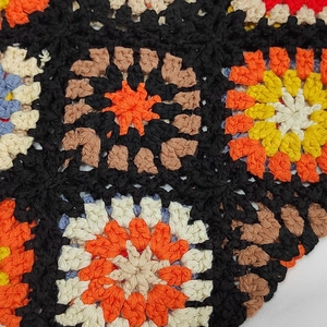 Close-up of handmade crochet bag showing colorful granny square patterns and stitch textures