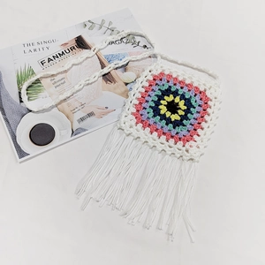 Detail of handmade crochet crossbody bag with colorful concentric circles and white tassels
