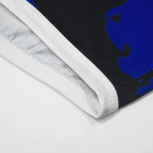 Detailed close-up of double-needle stitching and white hem on tie-dye printed beach shorts