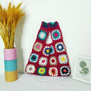 Handmade crochet granny square tote bag with vintage red base and floral knit patterns