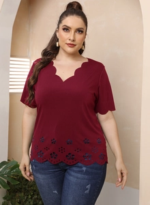 Close-up of deep burgundy V-neck top with delicate scalloped edges and cutout floral details
