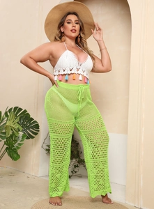 Detail of crochet halter top with colorful tassels and green mesh hollow beach pants