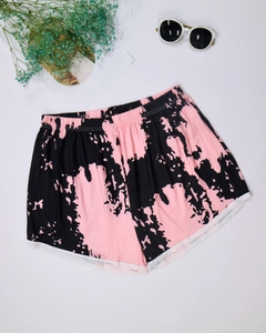 Detail of pink and black tie-dye beach shorts with elastic waist and white piping trim