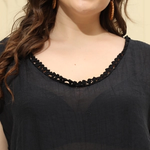 Dettaglio dello scollo a V con raffinato pizzo nero all'uncinetto su una blusa con volant