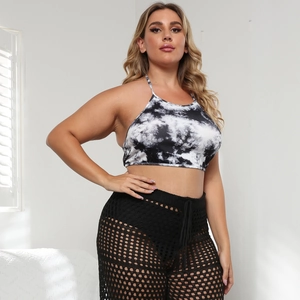 Detail of plus size tie-dye crop top and black high-waisted crochet beach trousers