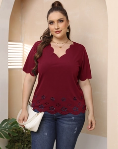 Detail of burgundy plus size top featuring scalloped V-neck and laser-cut floral hem