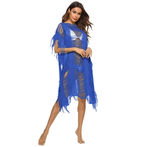 Detail of blue crochet beach cover-up featuring openwork knit and long tassel fringe