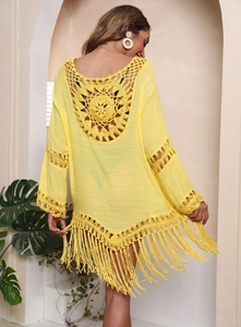 Detail eines Boho-Strand-Cover-ups mit Häkelmuster am Rücken und langen Fransen am Saum