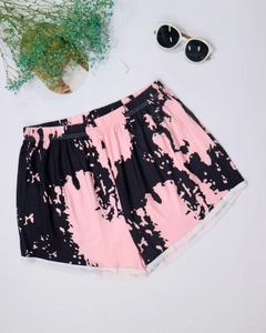 Flat lay of pink and black tie-dye beach shorts with elastic waist and white piping detail