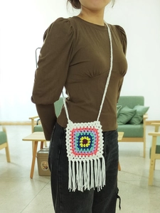 Handmade crochet crossbody bag with colorful granny square patterns and long white fringe
