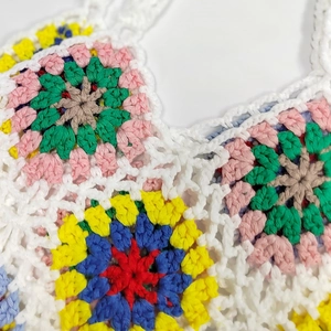 Close-up of handmade crochet granny square pattern with colorful yarn and white stitching