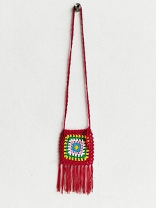 Close-up of handmade crochet bag featuring colorful granny square pattern and red tassels