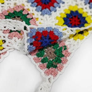 Detail of handmade crochet handbag showing colorful granny square patterns and white borders