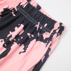 Detail of high-waisted elastic waistband on pink and black tie-dye beach shorts