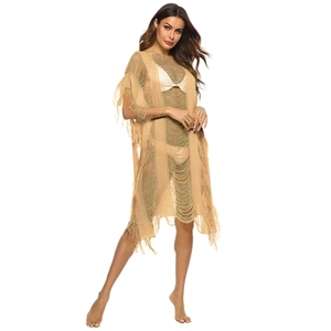 Detail of khaki crochet beach cover-up featuring openwork knit and long tassel fringe