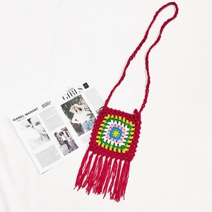 Detailed macro view of red crochet crossbody bag with floral granny square and long tassels