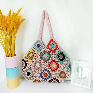 Handmade crochet tote bag with colorful granny square floral patterns on white background