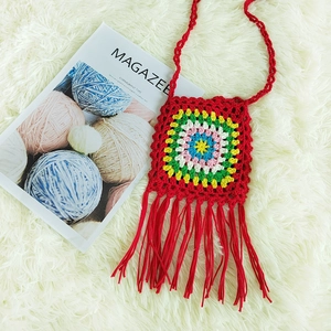 Detail of colorful handmade crochet crossbody bag with vibrant floral patterns and red tassels