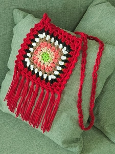 Detail of handmade crochet granny square crossbody bag with red fringes and strap