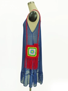 Detail of colorful granny square crochet bag with vibrant red fringe tassels on the side