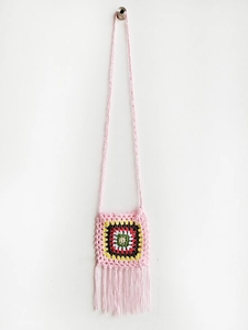 Detail of pink handmade crochet crossbody bag with granny square and long fringe