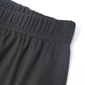 Detail of elastic waistband and black pleated fabric texture on women beach shorts
