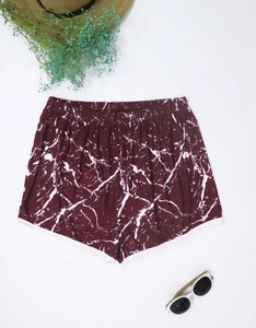 Flat lay of tie-dye beach shorts with sunglasses and straw hat for summer vibe