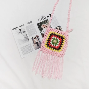 Detail view of pink crochet crossbody bag with colorful square patterns and long fringes