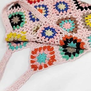 Detailed macro view of handmade pink crochet stitching and colorful floral granny squares