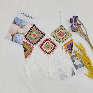 Detailed close-up of colorful handmade crochet pattern and long white fringe on the hem