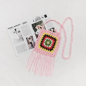 Detailed macro view of pink hand-crocheted bag featuring colorful mandala flower and tassels