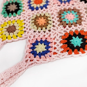 Close-up of pink handmade crochet bag with colorful granny square flower patterns