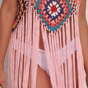 Close-up of Bohemian handmade crochet pattern and long pink fringe on beach cover-up dress