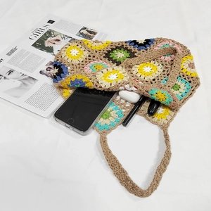 Detail of hand-crocheted tote bag interior showing daily items like phone and earbuds