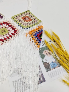 Detail of colorful crochet camisole featuring vibrant patchwork and long white fringe hem