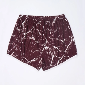 Detail of burgundy marble print beach shorts with elastic waistband and white piping