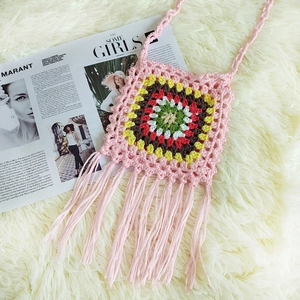 Detailed macro view of handmade pink crochet crossbody bag with colorful granny square and tassels