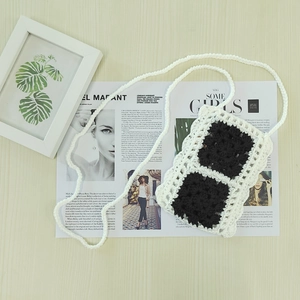 Detail of handcrafted crochet phone bag with black and white floral contrast weaving