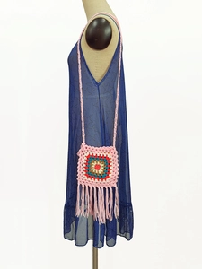Detail of colorful handmade crochet granny square crossbody bag with pink tassel fringe